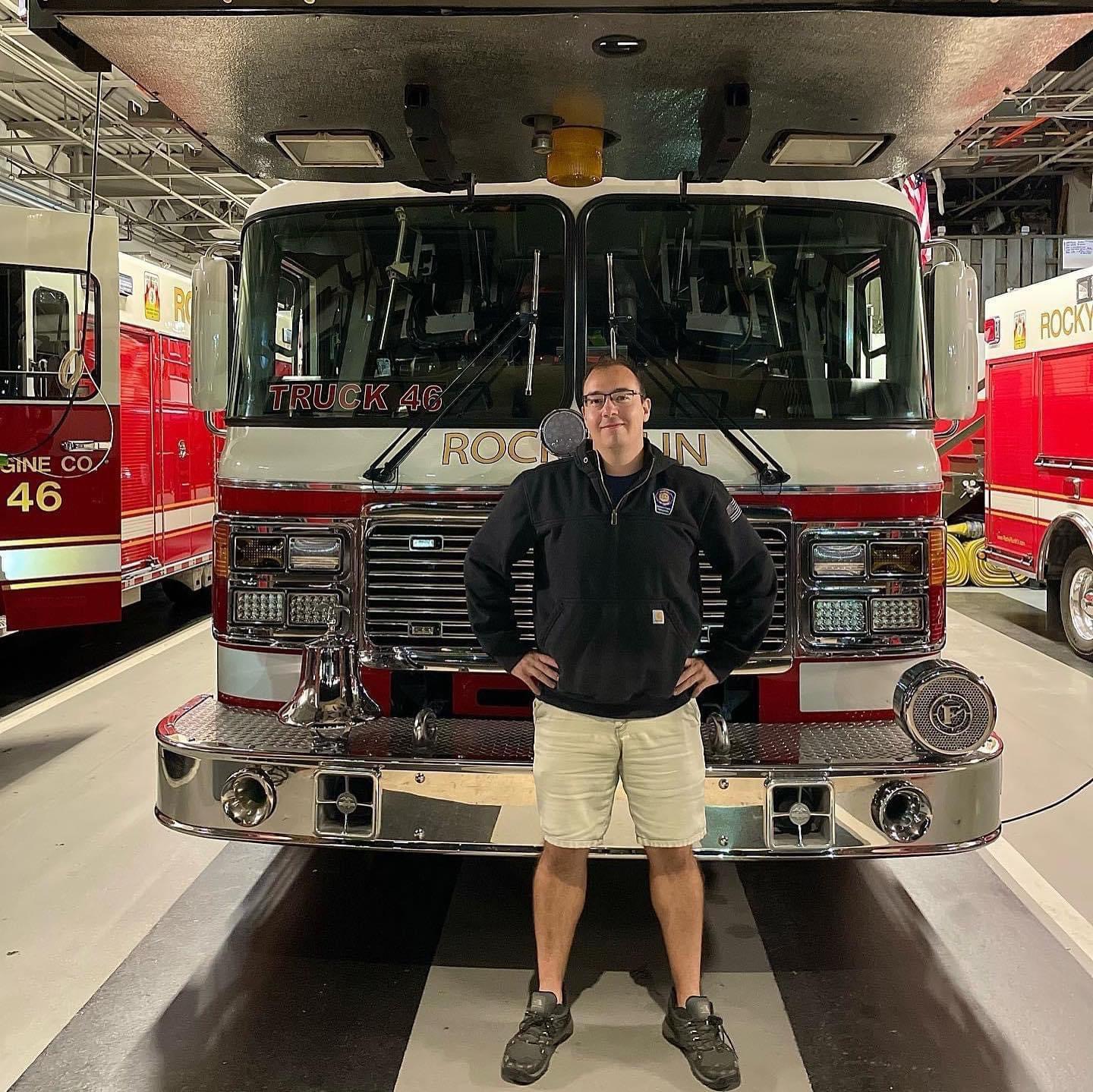 Sean Miller standing in front of a fire truck labeled Truck 46